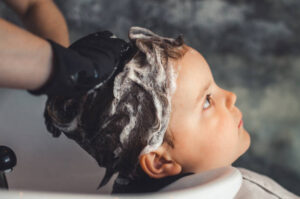 hands of a hairdresser with black latex gloves washing a child