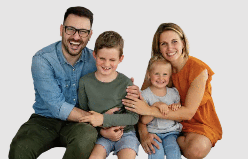 Parents haircut at The Great Bear Cut – Pasadena family salon Parent getting a haircut while holding two smiling children at The Great Bear Cut in Pasadena